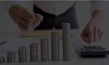 pilha de moedas com e uma pessoa com uma calculadora na mãe, fazendo alusão ao tema do artigo sobre Day trade