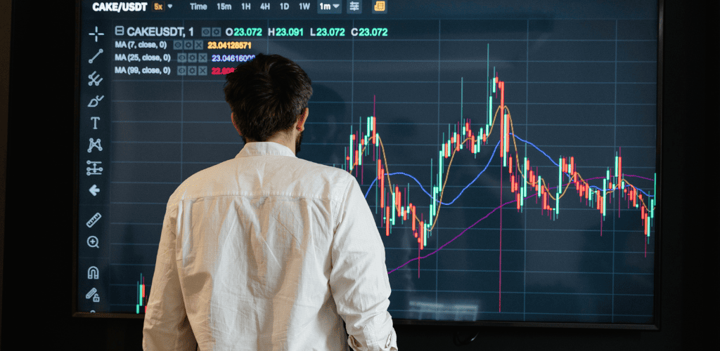 Homem olhando uma tela com gráficos de investimento