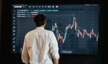 Homem olhando uma tela com gráficos de investimento
